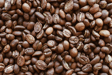 Dark brown natural coffee beans laying on a table. Ingredients for espresso, cappuccino or latte.
