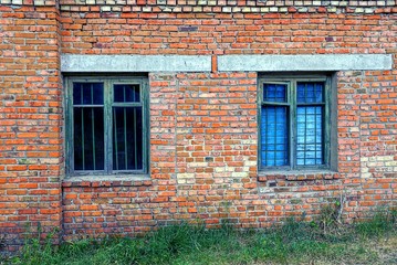 два старых окна за решёткой на кирпичной стене