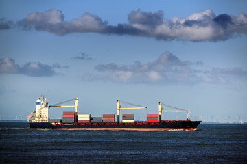 Large container ship in the north sea under a cloudy blue sky, copy space