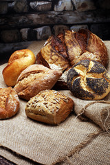 Different kinds of bread and bread rolls on wooden table