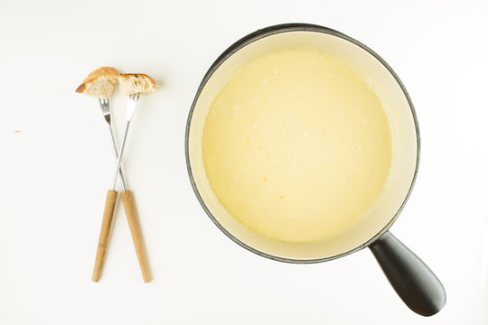 SWISS CHEESE FONDUE WITH BREAD, FORK AND POT ON WHITE BACKGROUND