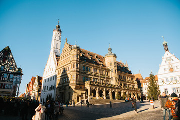 Obraz premium Rothenburg ob der Tauber, Germany, December 30, 2016: There are many tourists on the main square of the city during the Christmas holidays. Decorated houses in traditional style and the church.