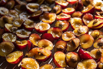 Sliced red plums for the cake on a grating, food or baking background