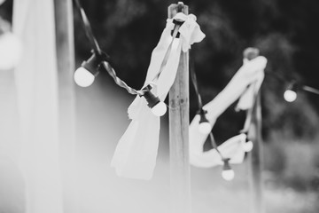 Light bulbs on a wire with white ornaments and torches on a beach