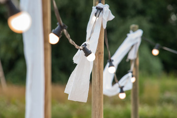 Light bulbs on a wire with white ornaments and torches on a beach