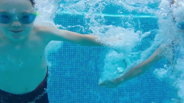 Brother and sister jump into swimming pool at the same time. slow motion underwater shot.