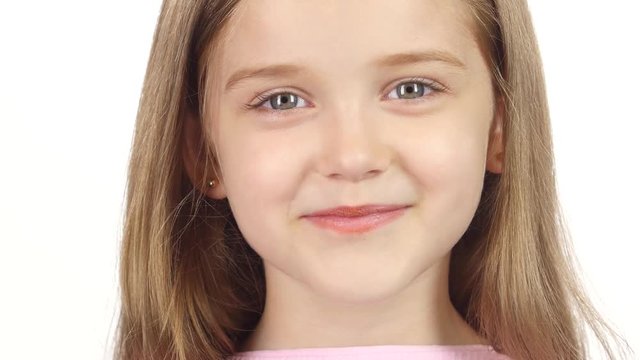 Little girl genuinely smile at the camera. White background. Close up