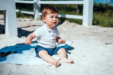 Little baby boy sitting on the sand