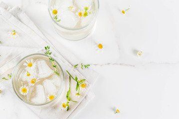 Summer refreshing drinks, infused herbal water, iced tea. Chamomile Honey and Whiskey Cocktail with thyme in glasses, on a white marble table. Copy space top view