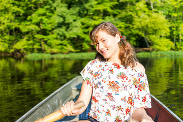 Happy smiling young woman rowing boat on lake in Virginia during summer