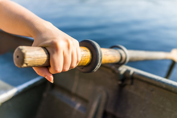 Female hand on row boat oar closeup in summer with water - Powered by Adobe