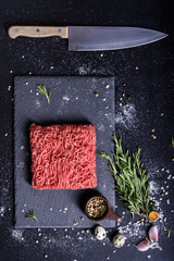 Red raw beef, cooking ingredients, kitchen knife. Top view.
