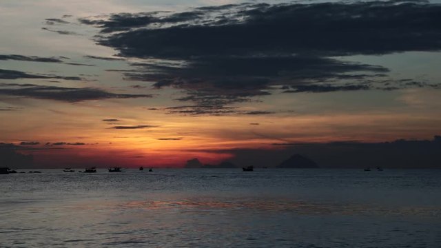 Sunrise with fishing boats and a tropical island looking out over the south China sea in Vietnam. High definition time lapse stock footage.