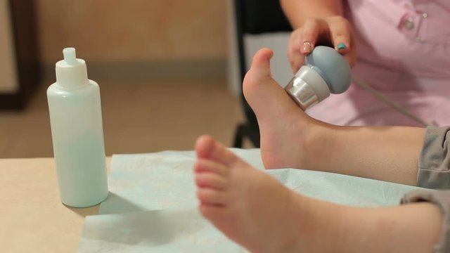 Ultrasound treatment for feet the small kid in the physiotherapy room.