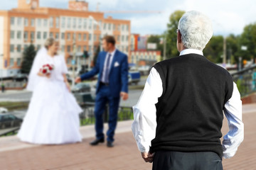 A man looks from afar on the newlyweds, a parent.