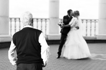 A man looks from afar on the newlyweds, a parent.