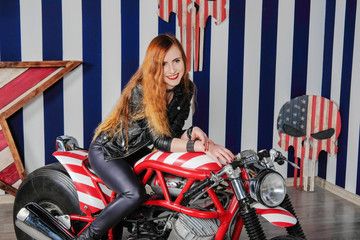 Naklejka na ściany i meble Young attractive woman dressed in leather sitting on a motorcycle in the studio.