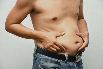 Asian fat man has cholesterol . He shows excess fat of the tummy. By hands use the squeeze at the his tummy. / Photo concept: fat, belly, obesity, cellulite