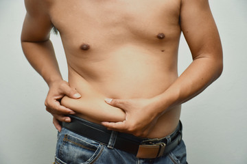 Asian fat man has cholesterol . He shows excess fat of the tummy. By hands use the squeeze at the his tummy. / Photo concept: fat, belly, obesity, cellulite