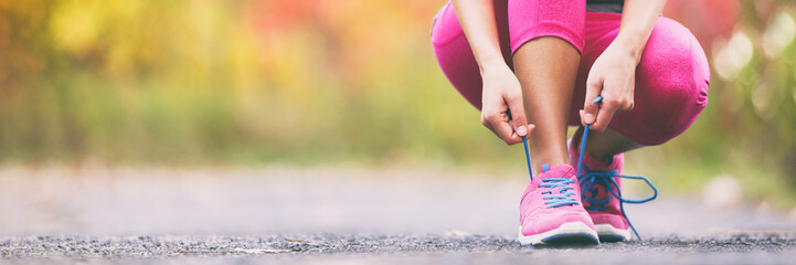 Loopschoenen runner vrouw veters binden voor herfst run in forest park panoramisch banner kopie ruimte. Joggen meisje oefenen motivatie heatlh en fitness.