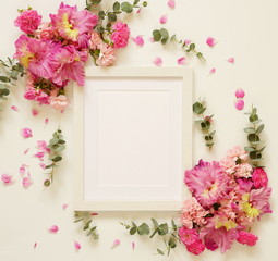 White photo frame and bouquets of pink flowers on a white background. top view. flat lay. copy space