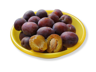 Синяя спелая слива в желтой тарелке на белом фоне