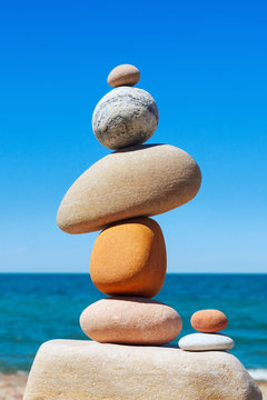 Colored stones stacked in a pile against the sea and blue sky