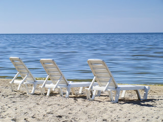 Three sun loungers on a deserted beach