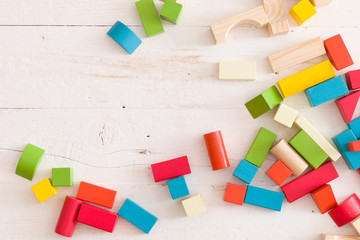 Top view on colorful wooden bricks on the white table background. building with geometric shapes....