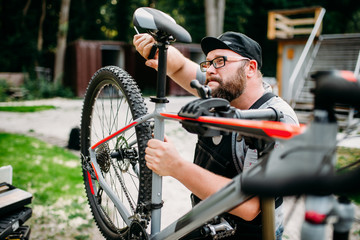 Fototapeta na wymiar Bicycle mechanic adjusts with tools bike seat