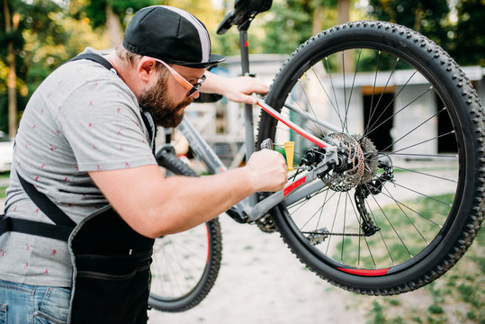 Bicycle mechanic adjusts back disk brakes
