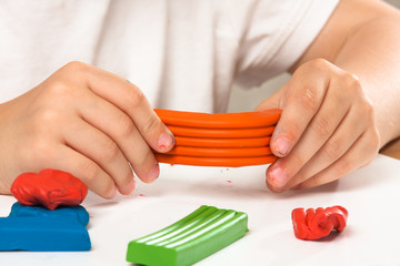 Fototapeta premium hands of child with piece of orange plasticine