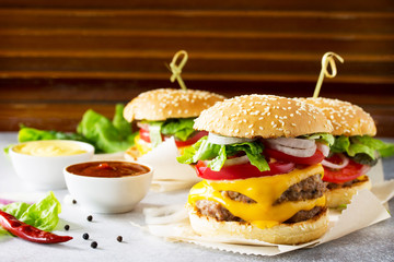 A delicious fresh homemade hamburger on a slate or stone table. Double cheeseburger with the meat cutlet and vegetables. Street food, fast food. Copy space.