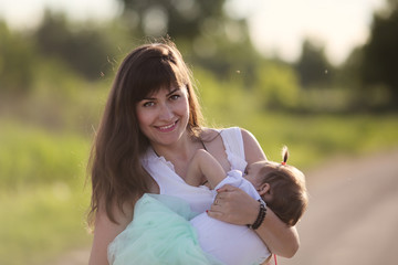 Stylish mom breastfeeding her daughter, nature