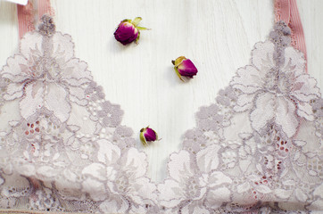 Lace lingerie on the white wooden background. Women's fashion underwear with dried roses