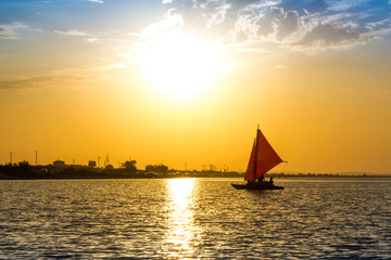 The sailboat sails to the shore at sunset
