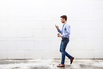 Young motivation Businessman using smart phone while walk outdoor building, Lifestyle of modern male, Technology to Communicate in Business concept