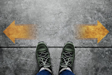 Making Decision Concept, Top view of Male with Casual Adventure shoes with Arrow Left and Right present over Grunge Cement Concrete Crossroad Background