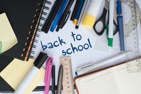 School set with back to school inscription in notebook and stationery on wooden background
