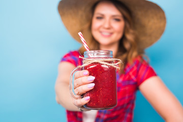 Close up studio portrait of sexy woman wearing bright outfit holding and drinking tasty green smoothie milkshake. Over blue background and copy space