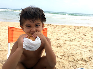 Niño comiendo en la playa