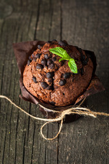 chocolate dark muffin with a leaf of mint on a wooden table with cinnamon, anise, chocolate