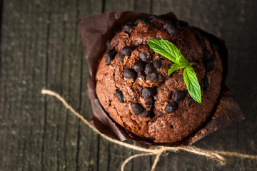 chocolate dark muffin with a leaf of mint on a wooden table with cinnamon, anise, chocolate