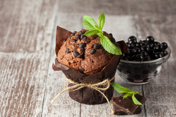 chocolate dark muffin with a leaf of mint on a wooden table with cinnamon, anise, chocolate