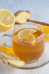 A glass cup of green natural tea with ginger, lemon, mint and honey on wooden rustic background. Healthy drink.