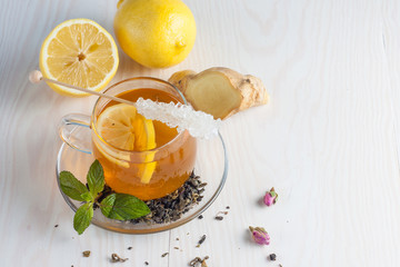 A glass cup of green natural tea with ginger, lemon, mint and honey on wooden rustic background. Healthy drink.