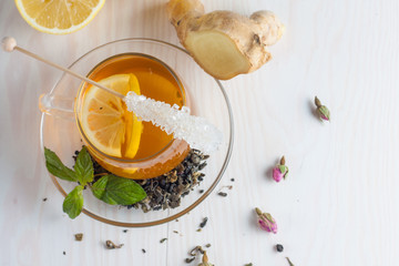 A glass cup of green natural tea with ginger, lemon, mint and honey on wooden rustic background. Healthy drink.