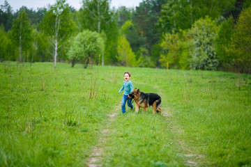 Obraz na płótnie Canvas Little boy with a huge dog stands in the middle of a dirt road on a green meadow