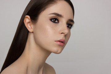 The young beautiful brunette with face freckles. Smoky cosmetics in eyes and gentle sensual lips, long neck. Correction of hair, stratification, Spa, beauty shop