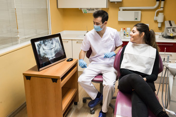 Dentist communicating with female client about x-ray shot in clinic.